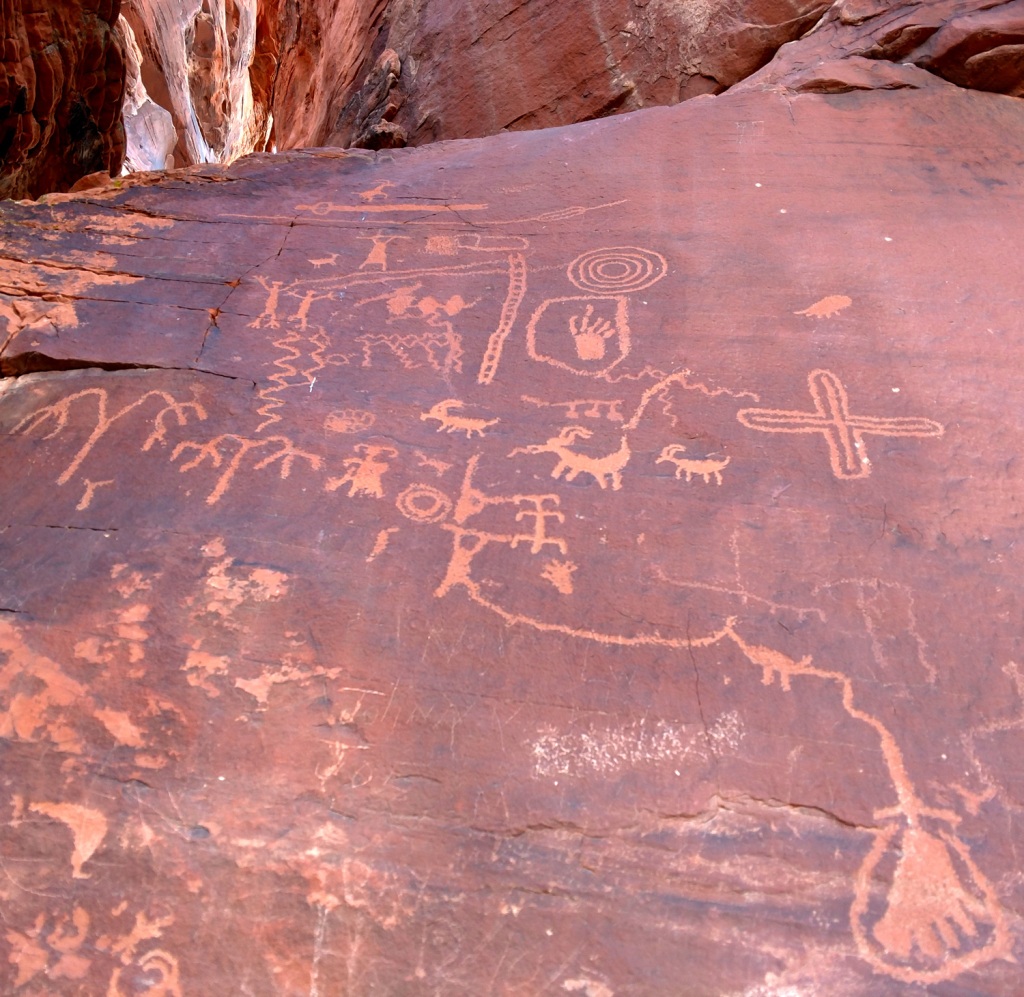 A foot, a line like a road, a stick figure using an atlatl, goats, a ladder, spirals to indicate the season, and other petroglyphs